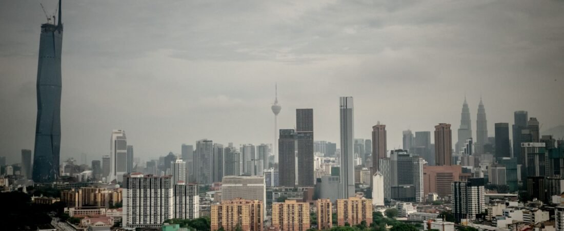 kuala lumpur haze Aerial view of Kuala Lumpur skyline featuring Petronas Towers and KL Tower shrouded in cloudy sky.